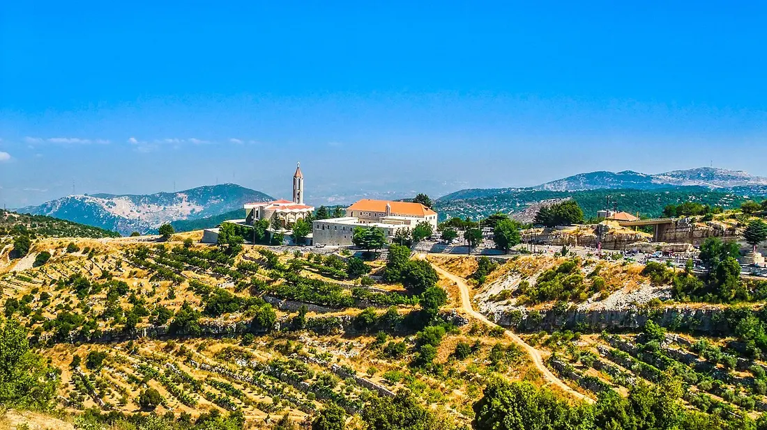 The Monastery of Saint Maron in Annaya seen across the valley, with the church and forested mountainside