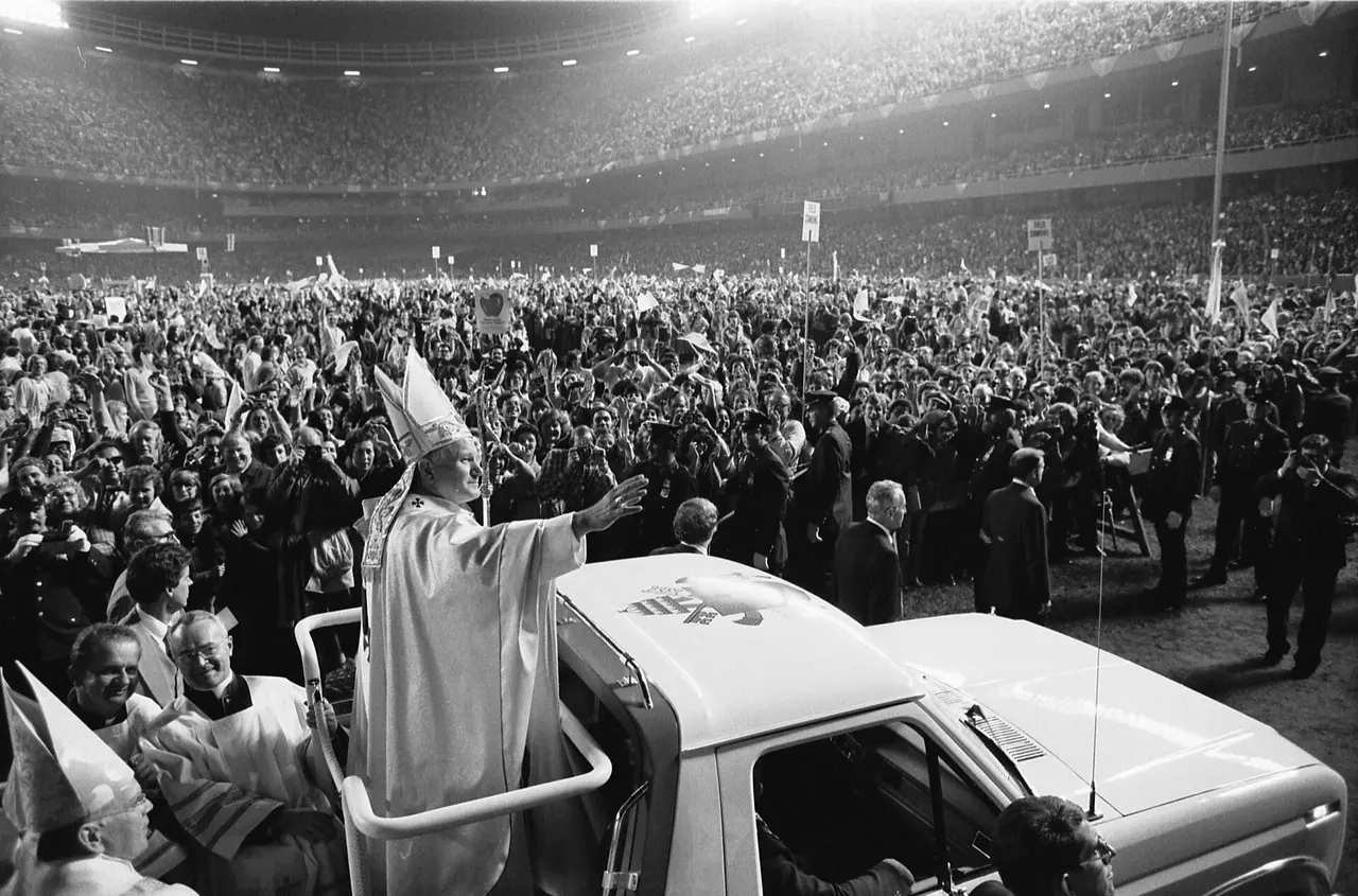 Pope John Paul II in 1979, smiling and raising his hand in blessing