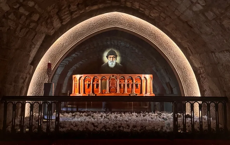 Arched tomb chamber at Annaya with a candle-lit icon of Saint Charbel above the reliquary