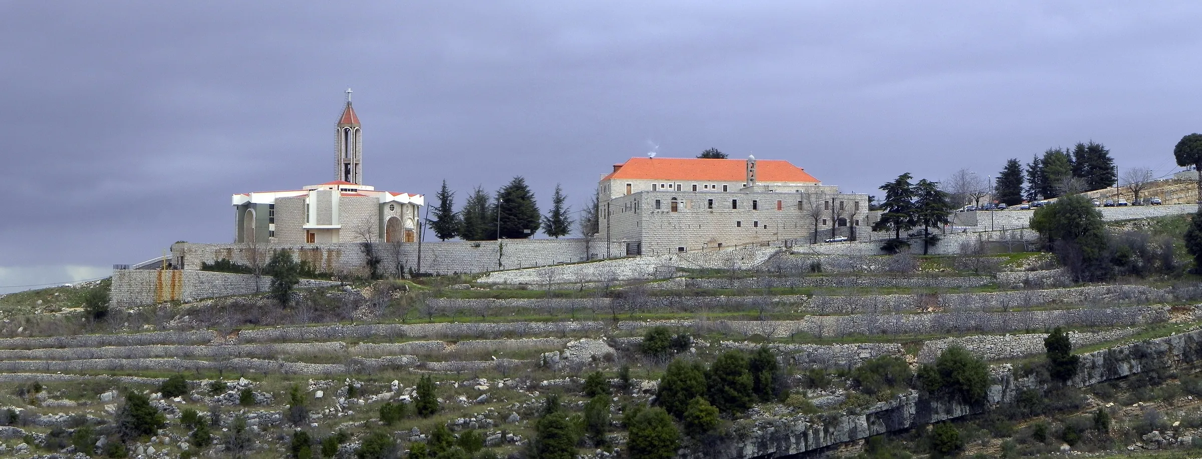 The church and monastery of Saint Maron at Annaya on a terraced mountainside in winter, with a bell tower and a red-tiled roof
